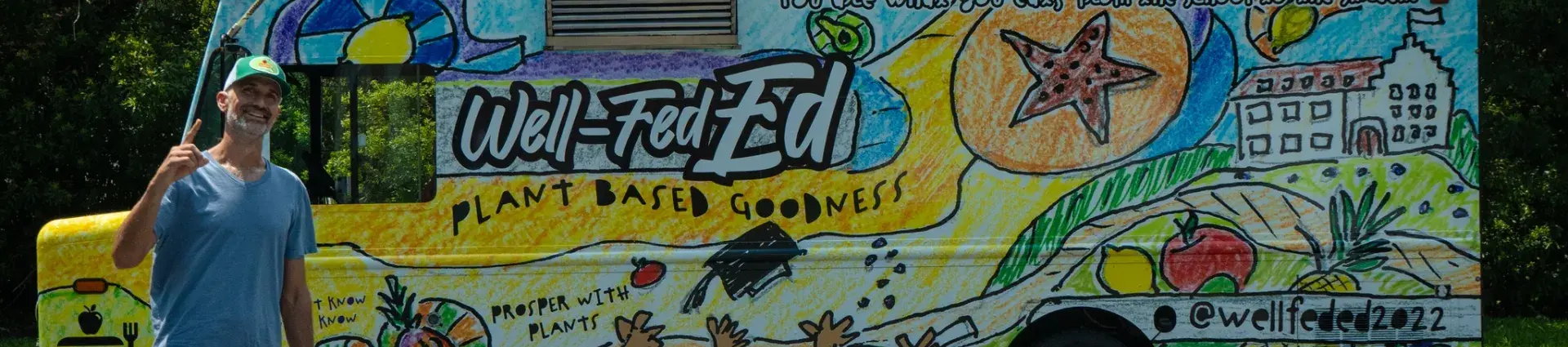 Well-Fed Ed's food truck with owner, Lucas, standing in front of the truck